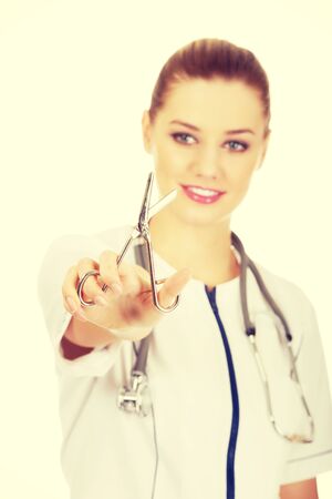 Happy female doctor with scissors in hand.の写真素材