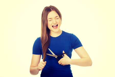 Angry screaming teenager cutting her hair.の写真素材