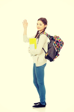 Teenager girl with school backpack waving hand.の写真素材