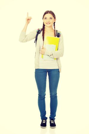 Teenager girl with school backpack pointing up.の写真素材