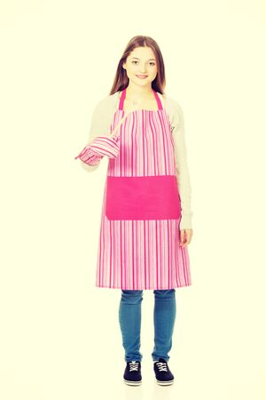 Teen woman in kitchen apron holding wooden spoon.の写真素材