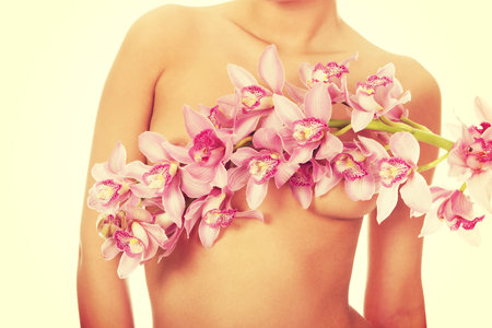Beautiful woman covering breast with flower.の写真素材
