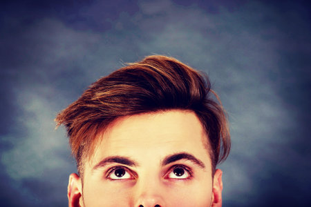 Handsome young man with brown eyes looking up.の写真素材