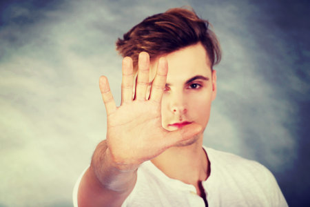 Young handsome man showing stop sign.