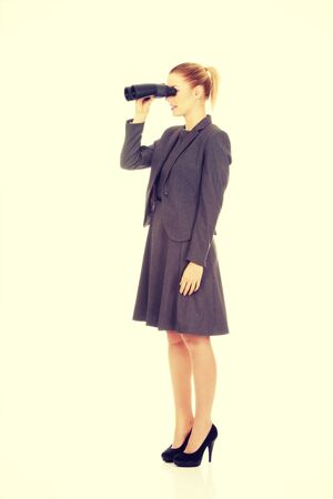 Caucasian businesswoman looking through binoculars.の写真素材
