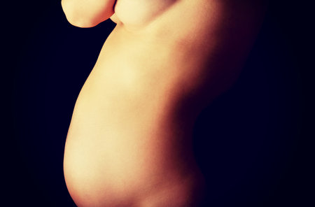 Woman touching her growing pregnant belly