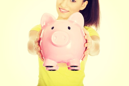 Happy teenage woman holding piggybank.の写真素材