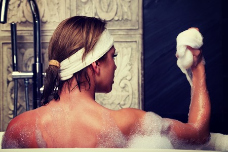 Beautiful bathing woman cleaning herself with sponge.の写真素材