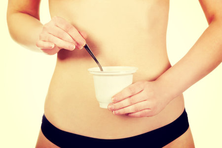 Beautiful woman in underwear eating yogurt.の写真素材