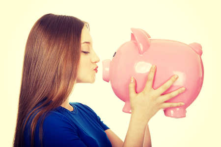 Happy teenage woman kissing piggybank.の写真素材