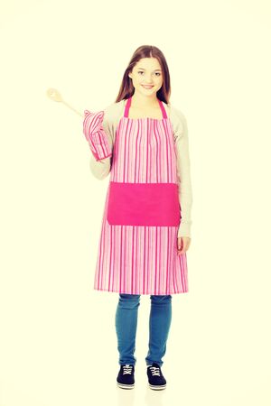 Teen woman in kitchen apron holding wooden spoon.の写真素材