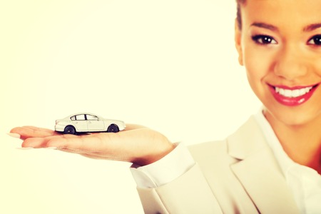 African businesswoman holding small car on palm.の写真素材