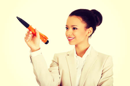African businesswoman pointing up with big pen.の写真素材