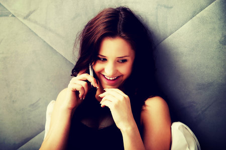 Relaxed woman talking on the phone in bedroom.