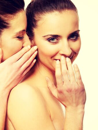 Beautiful two women sharing a secret.の写真素材