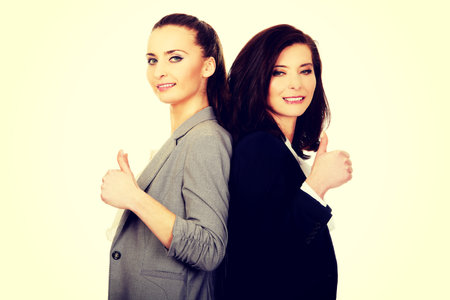 Two smiling businesswomen with thumbs up gesture.の写真素材