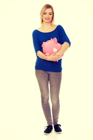 Happy young woman holding piggybank.の写真素材