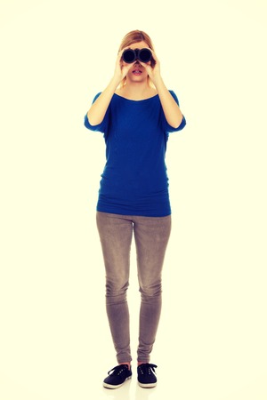Young woman looking through binoculars.の写真素材