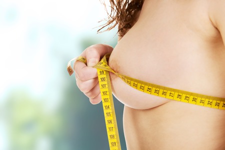 Slim undressed woman measuring her breast.の写真素材