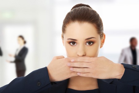 Portrait of young businesswoman covering with hand her mouthの写真素材