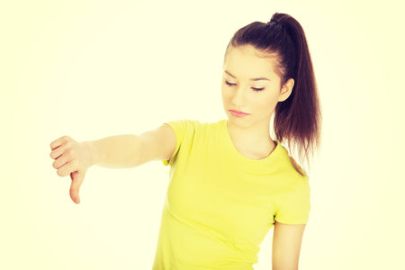 Young unhappy student woman showing thumbs down.