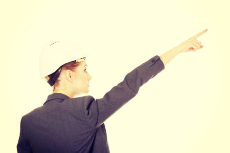 Caucasian businesswoman in hard hat pointing up.の写真素材