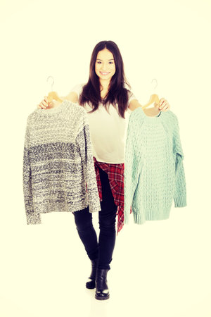 Teen with two sweaters thinking what to dress.