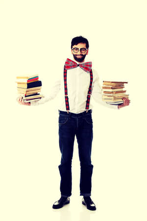 Handsome man wearing suspenders holding stack of books.の写真素材