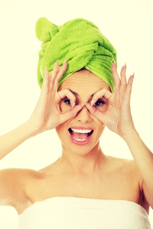 Young woman watching through fingers okay glasses.の写真素材