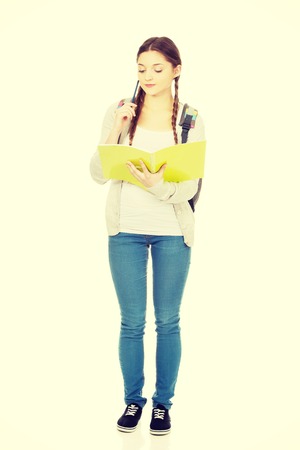 Thoughtful teenage girl with school backpack holding folders.の写真素材