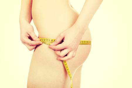 Slim undressed woman measuring her hips.の写真素材