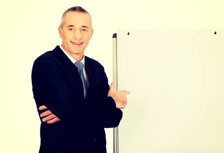 Mature businessman with marker pointing on flip chart.の写真素材