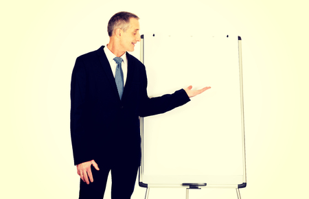 Mature businessman presenting something on flip chart.の写真素材