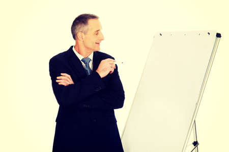 Mature businessman with marker standing near flip chart.の写真素材