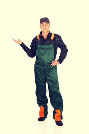 Experienced gardener in uniform showing space on the leftの写真素材