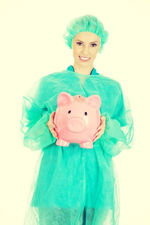 Female surgeon doctor with piggy bank.の写真素材