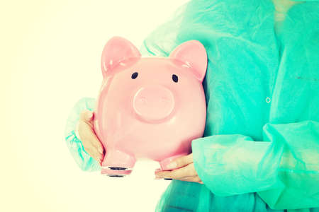Female surgeon doctor with piggy bank.の写真素材