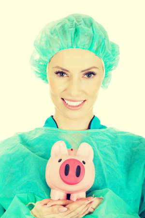 Female surgeon doctor with piggy bank.の写真素材
