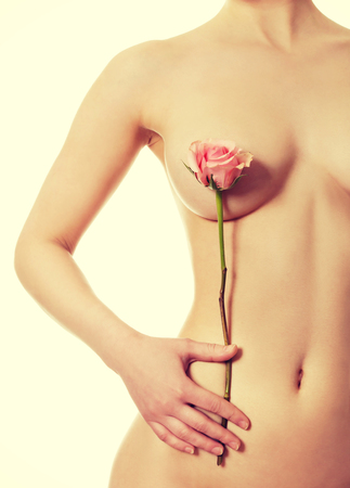 Beautiful woman covers breast with flower.の写真素材