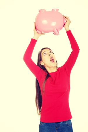 Shocked young student woman with piggybank.の写真素材