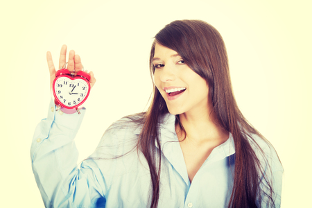 Young morning woman in big shirt holding alarm clock.の写真素材
