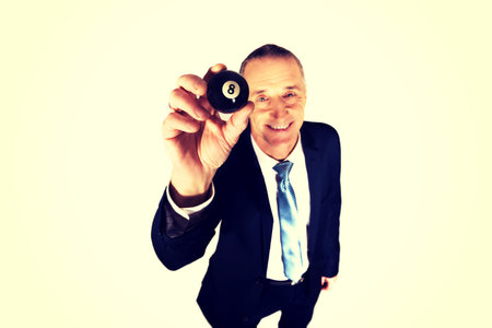 Businessman holding billiard eight ball in his hand.