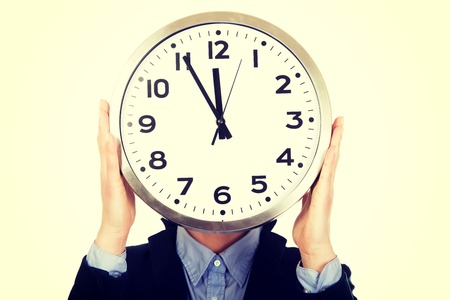 Beautiful business woman hiding behind big clock.の写真素材