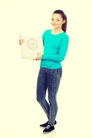 Happy beautiful teenager holding a scale.の写真素材