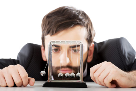 Businessman moving newton balls in office.