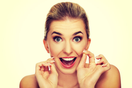 Young caucasian woman flossing her teeth, isolated on white