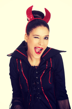 Beautiful woman in devil carnival costume blinks eye.