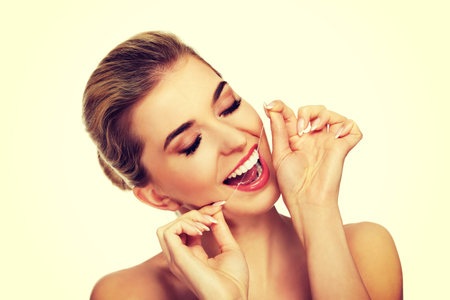 Young caucasian woman flossing her teeth, isolated on white