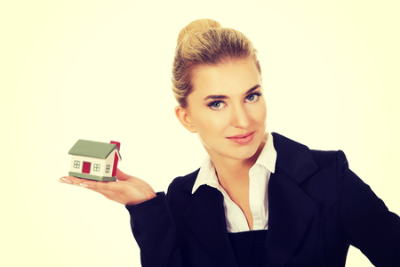 Happy businesswoman holding a house model.の写真素材