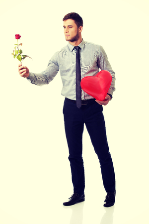 Young happy man with red rose and heart balloon.の写真素材
